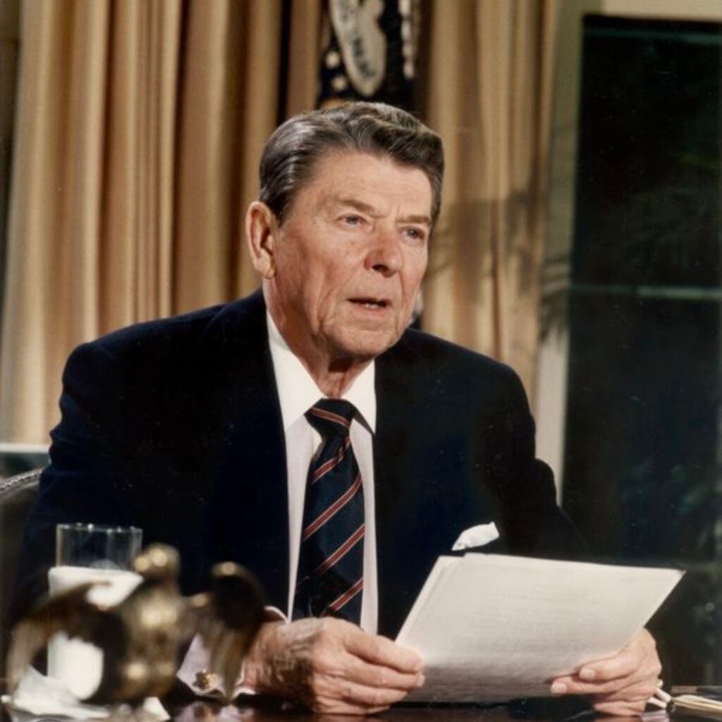Ronald Reagan sits behind his desk in the Oval Office